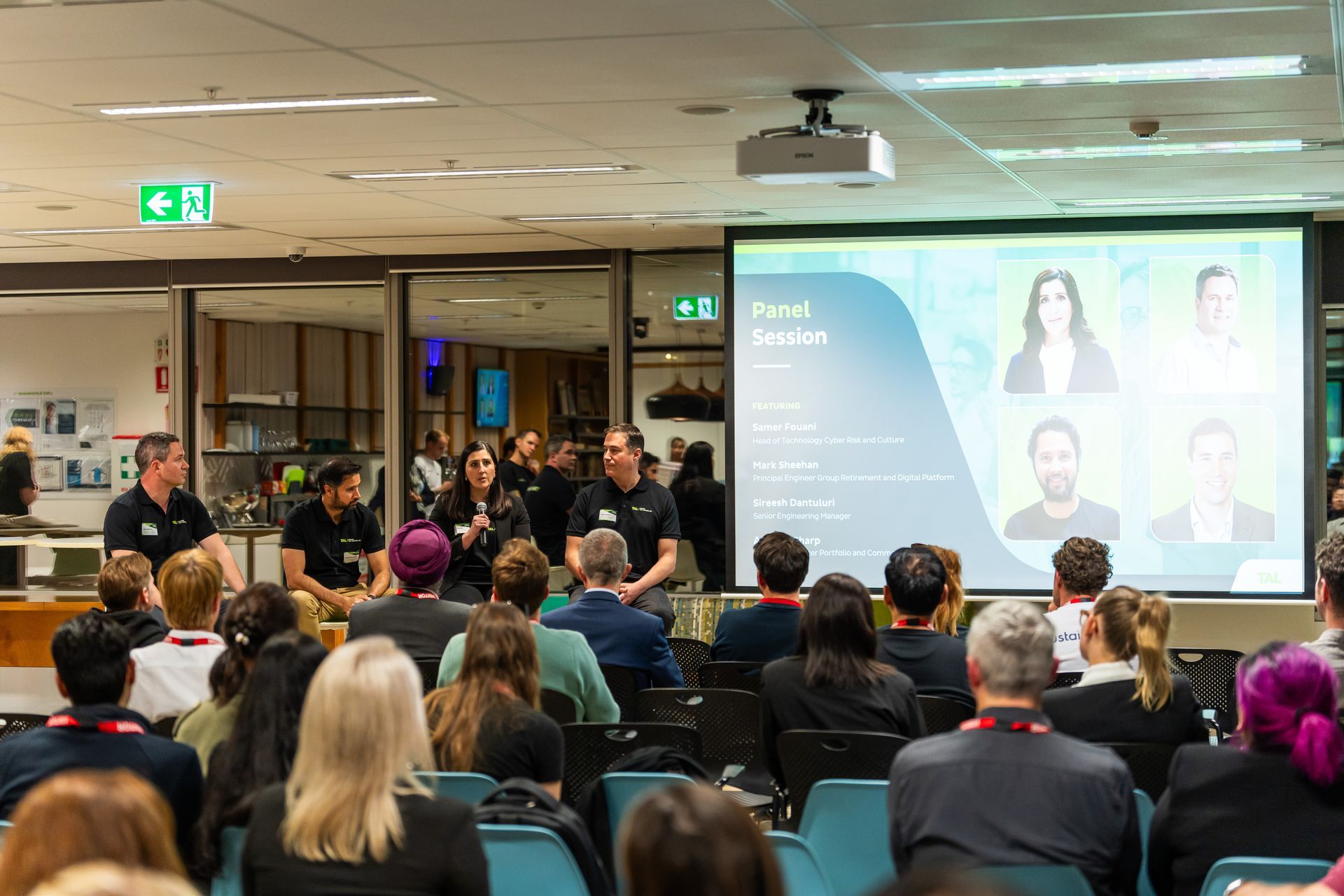 A group of people are sitting in front of a projector screen.