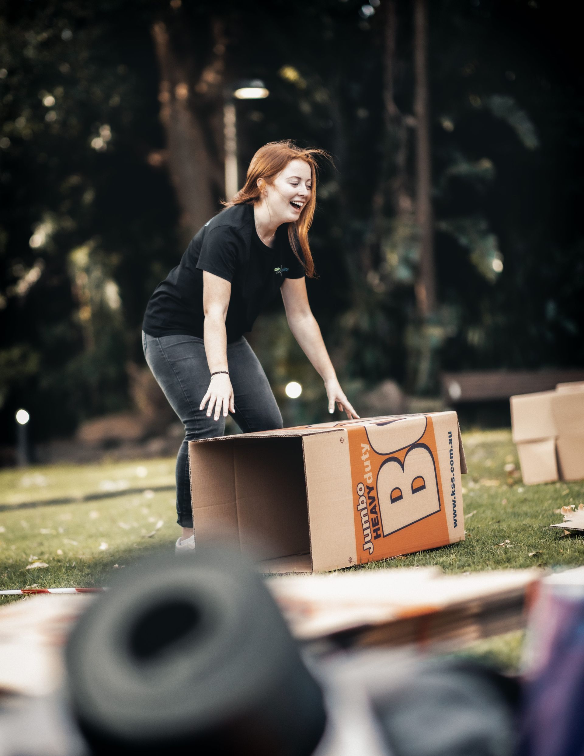 A woman is kneeling on top of a cardboard box.