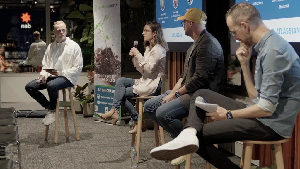 A group of people are sitting on stools in a room.