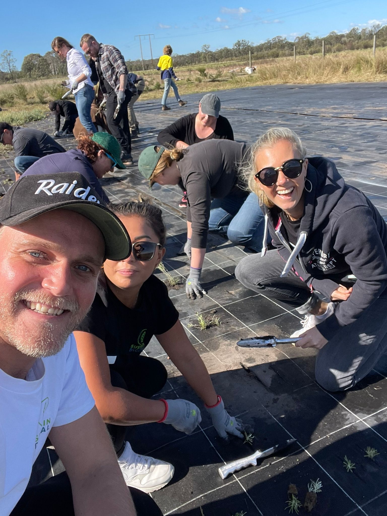 A group of people are kneeling on the ground in a field.