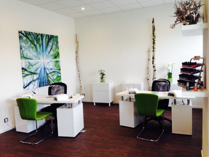 Ein Zimmer mit zwei Schreibtischen und grünen Stühlen und einem Gemälde an der Wand