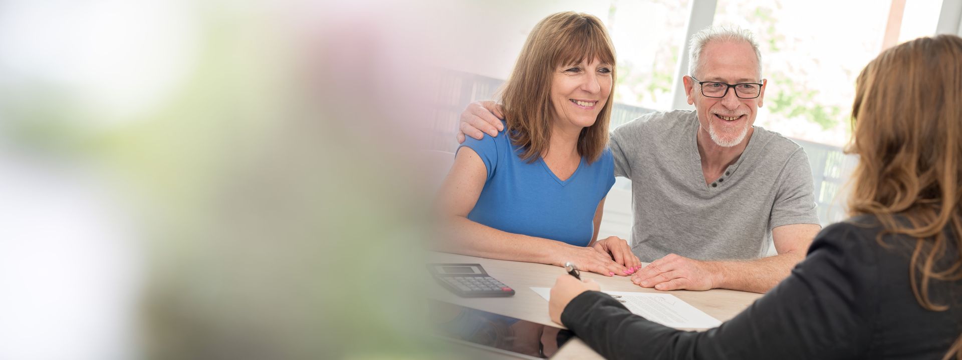 A man and a woman are sitting at a table talking to a woman.