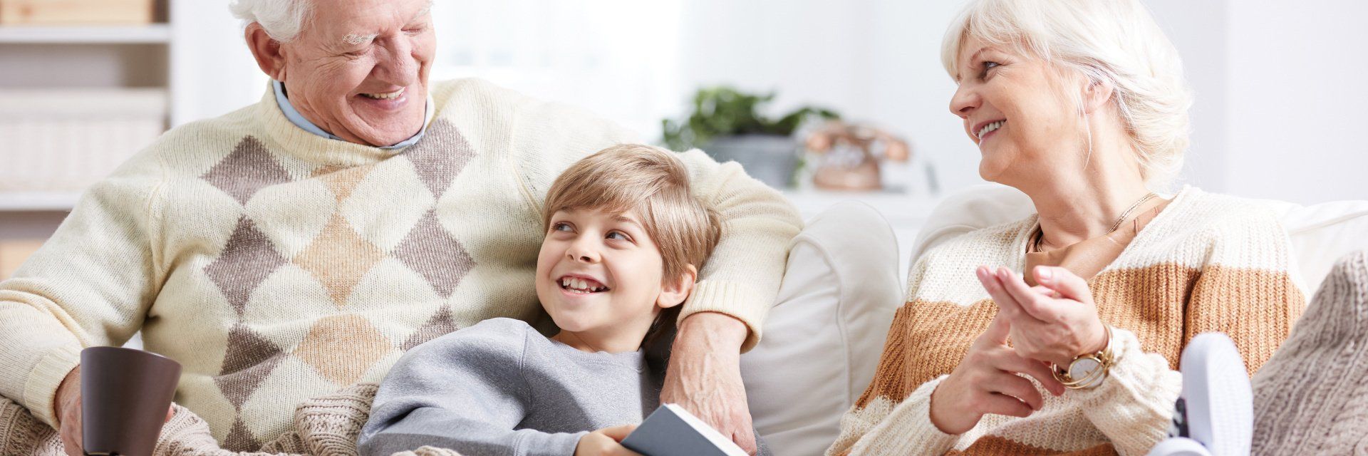 An elderly couple and a young boy are sitting on a couch.