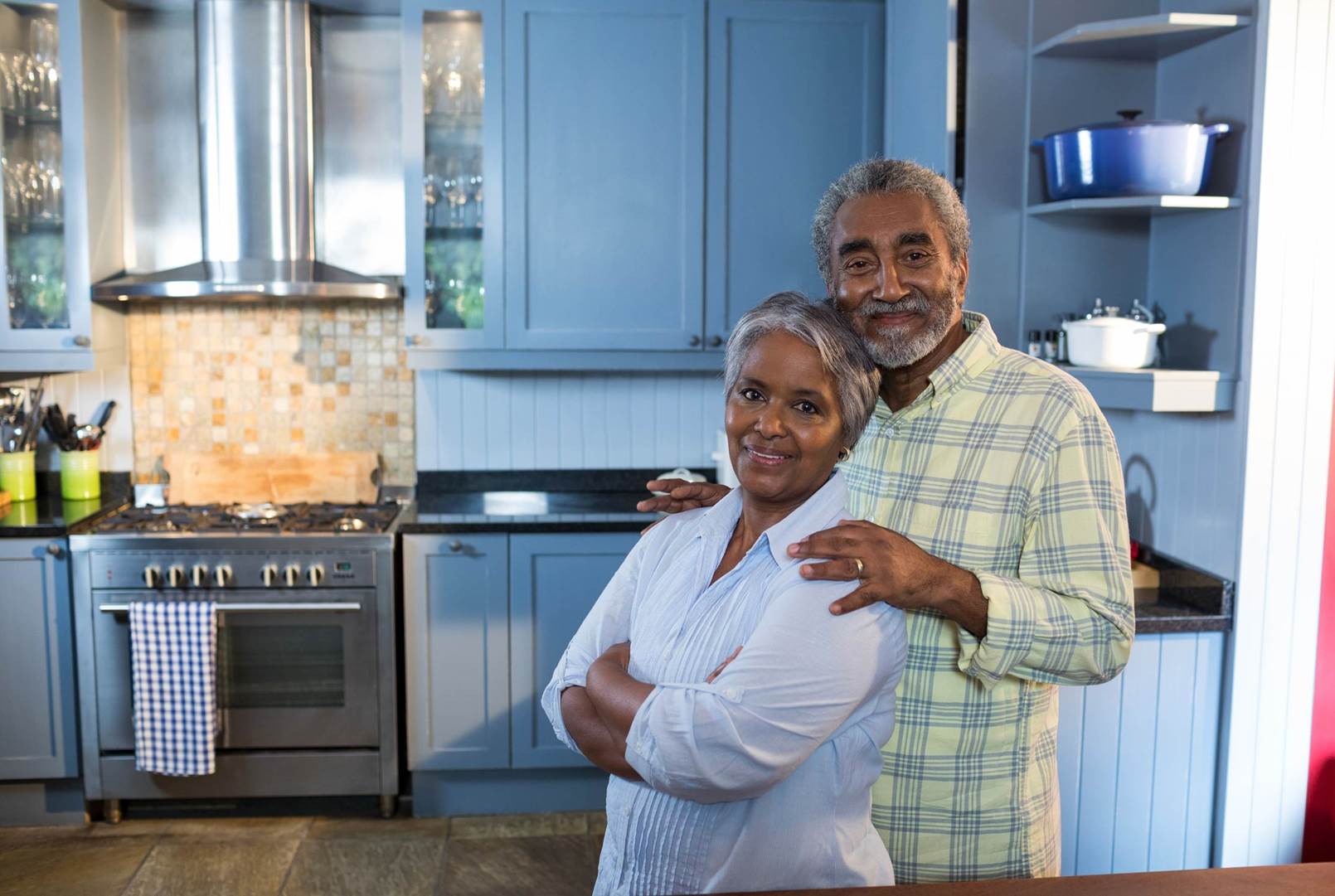 A man and a woman are posing for a picture in a kitchen.