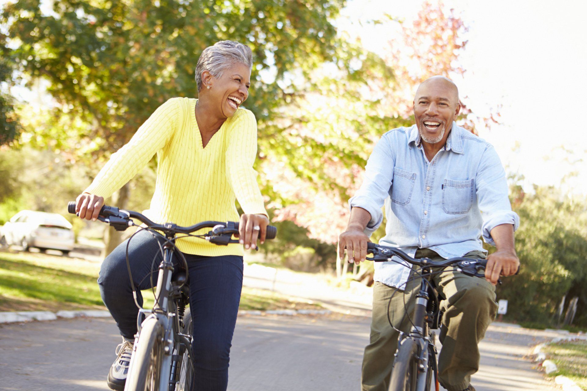 A man and a woman are riding bicycles down a street.