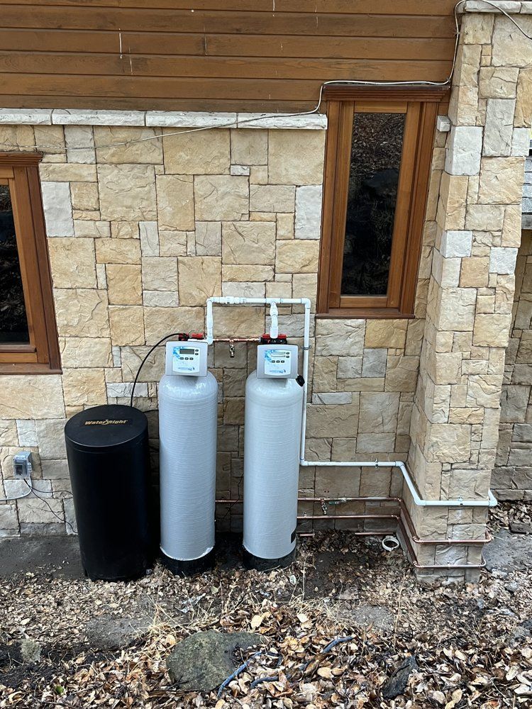 Two water filters are sitting outside of a brick building.