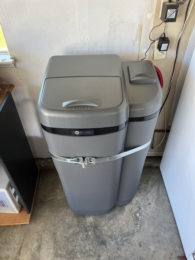 A water softener is sitting on the floor in a garage.