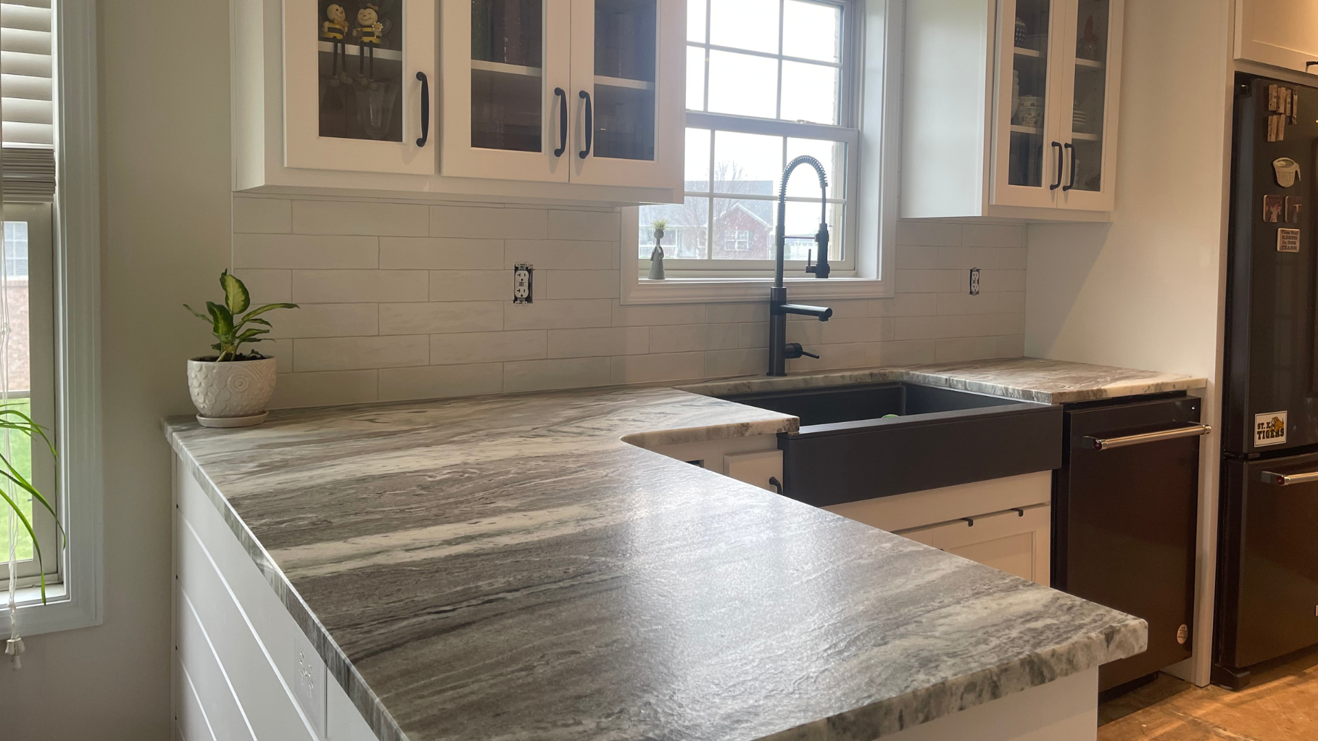 Modern kitchen with white cabinets, gray countertops, and black fixtures.