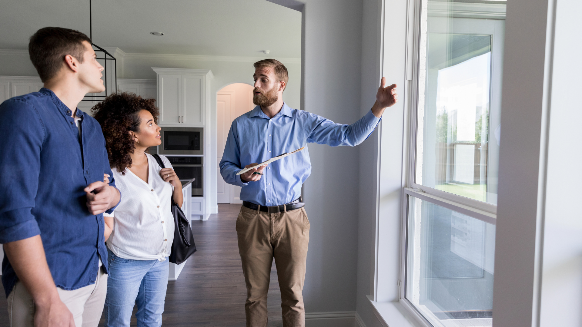 Real estate agent points out features of a home to a couple.