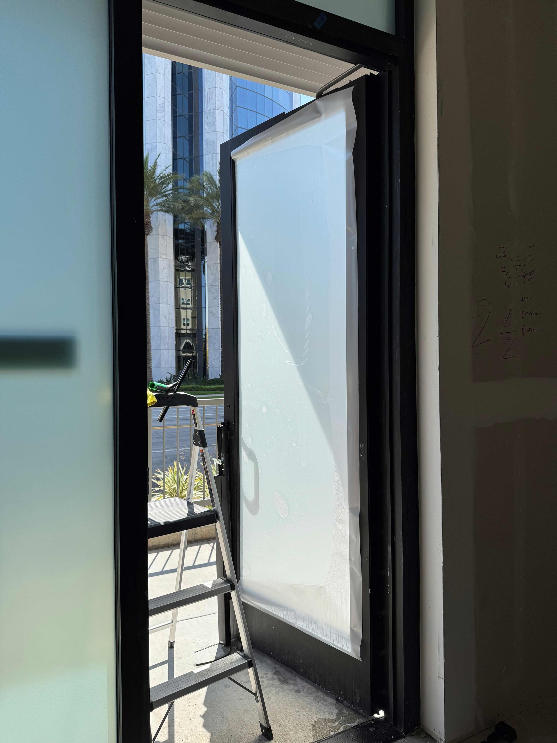 Open doorway with frosted glass, ladder, view of outside building.