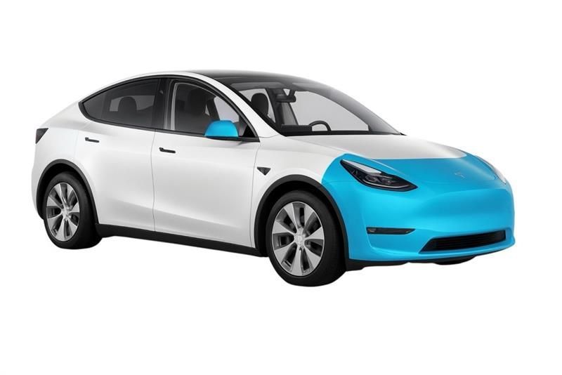 Car being wrapped in clear protective film, in a brightly lit garage.