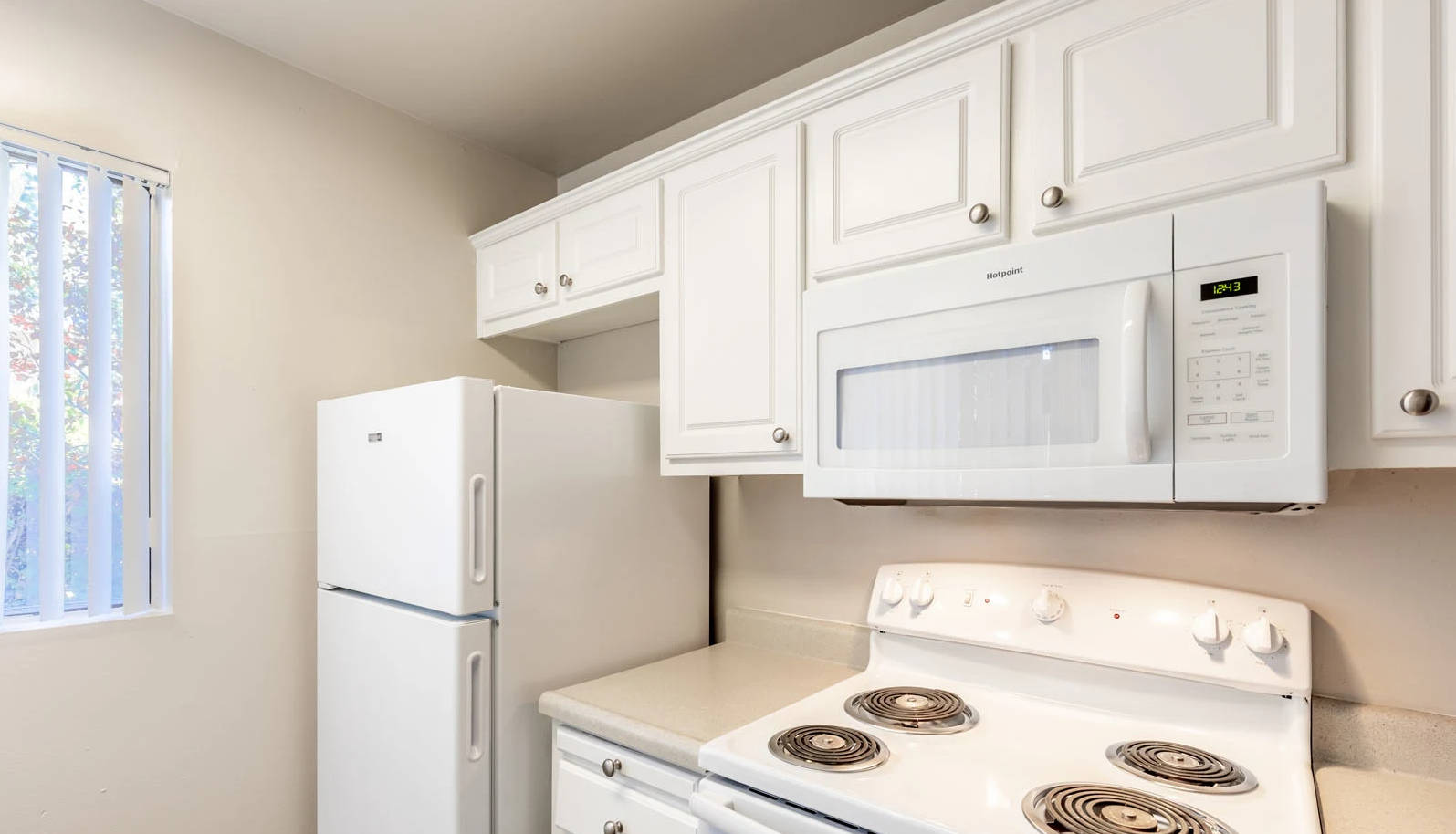 Ascent on Steamboat  kitchen with a stove , refrigerator , microwave and white cabinets.