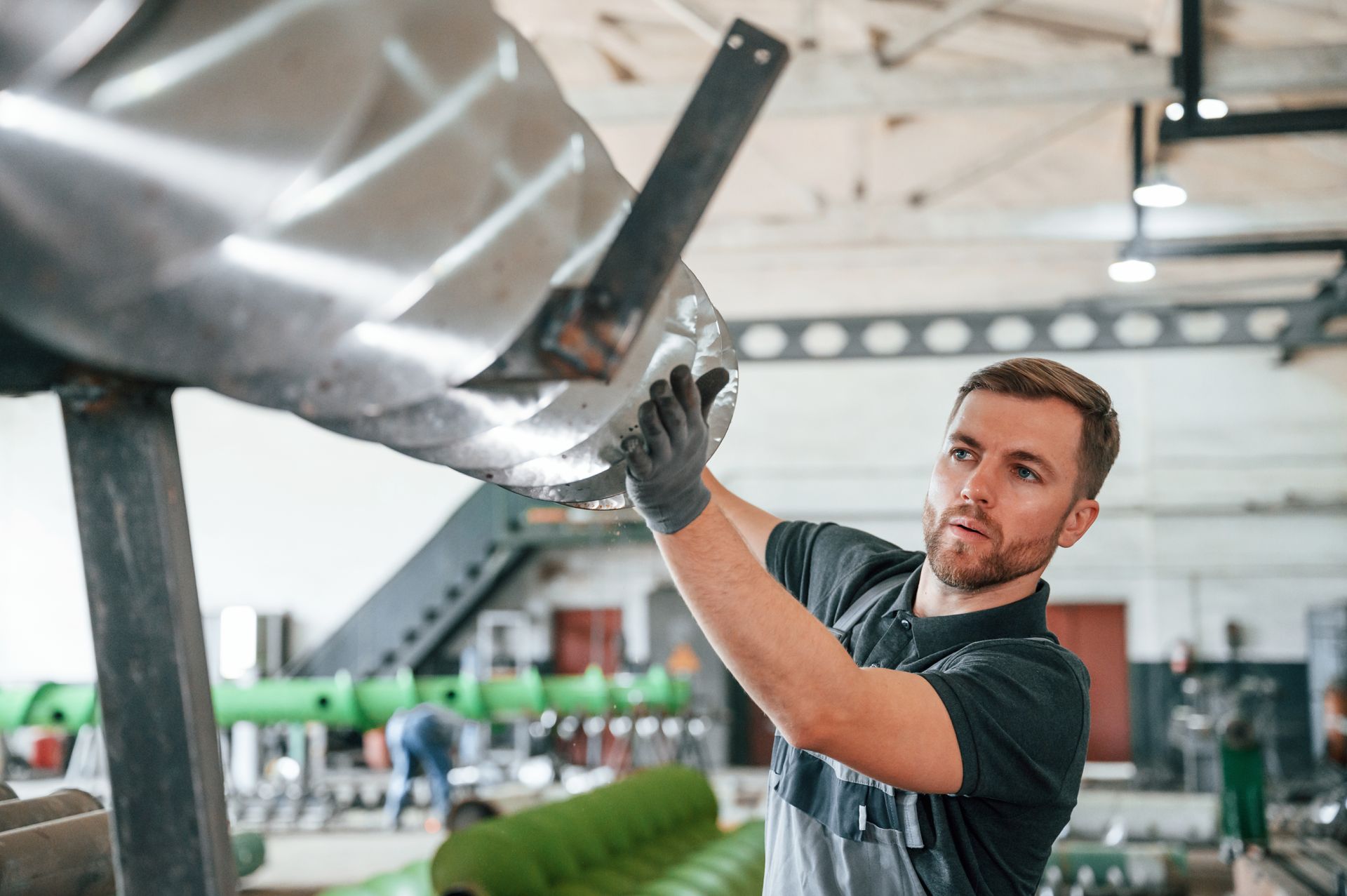 Worker sanding a metal surface in a bright workshop