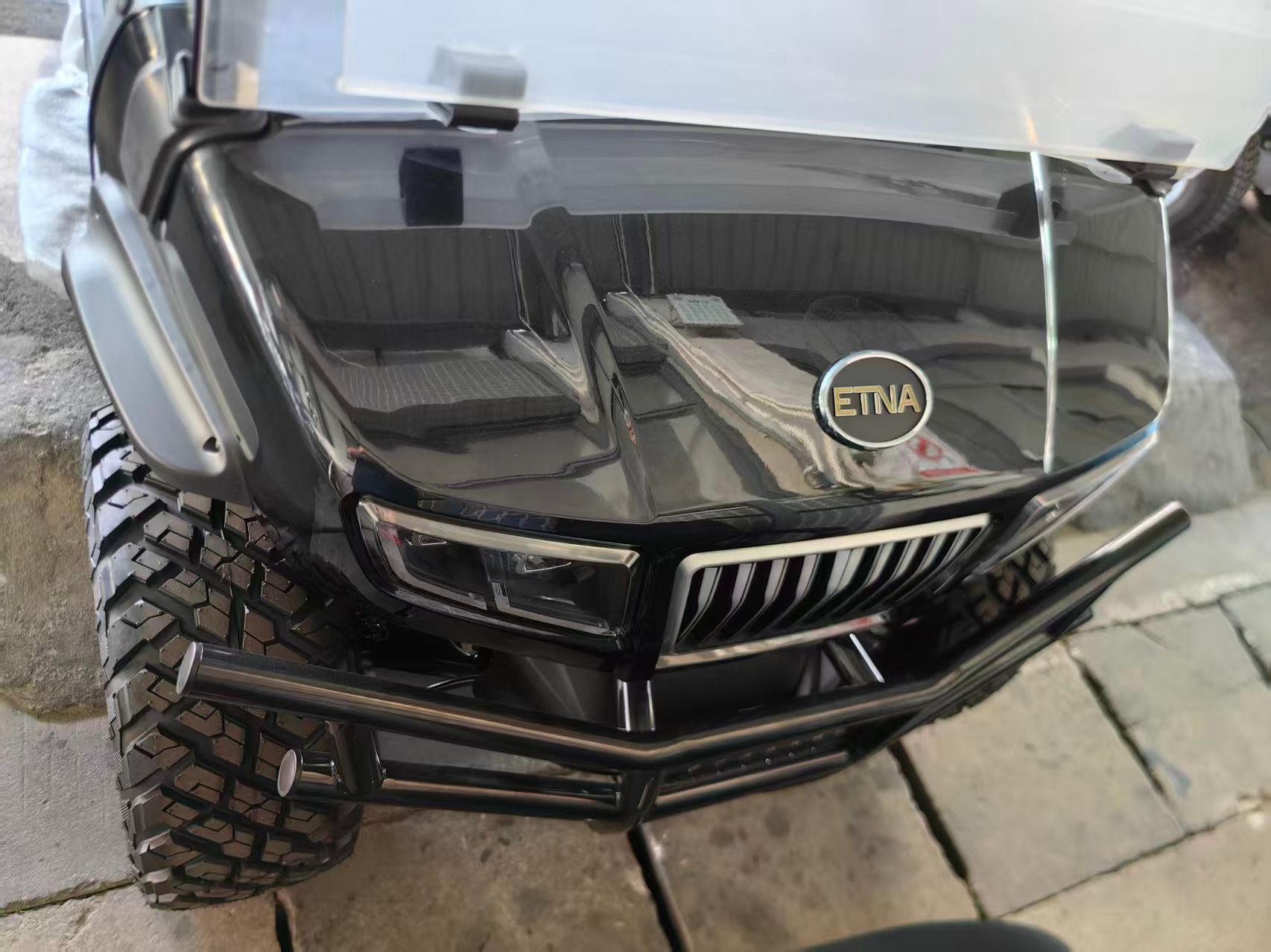 Black ATV front view with off-road tires, a bull bar, and 