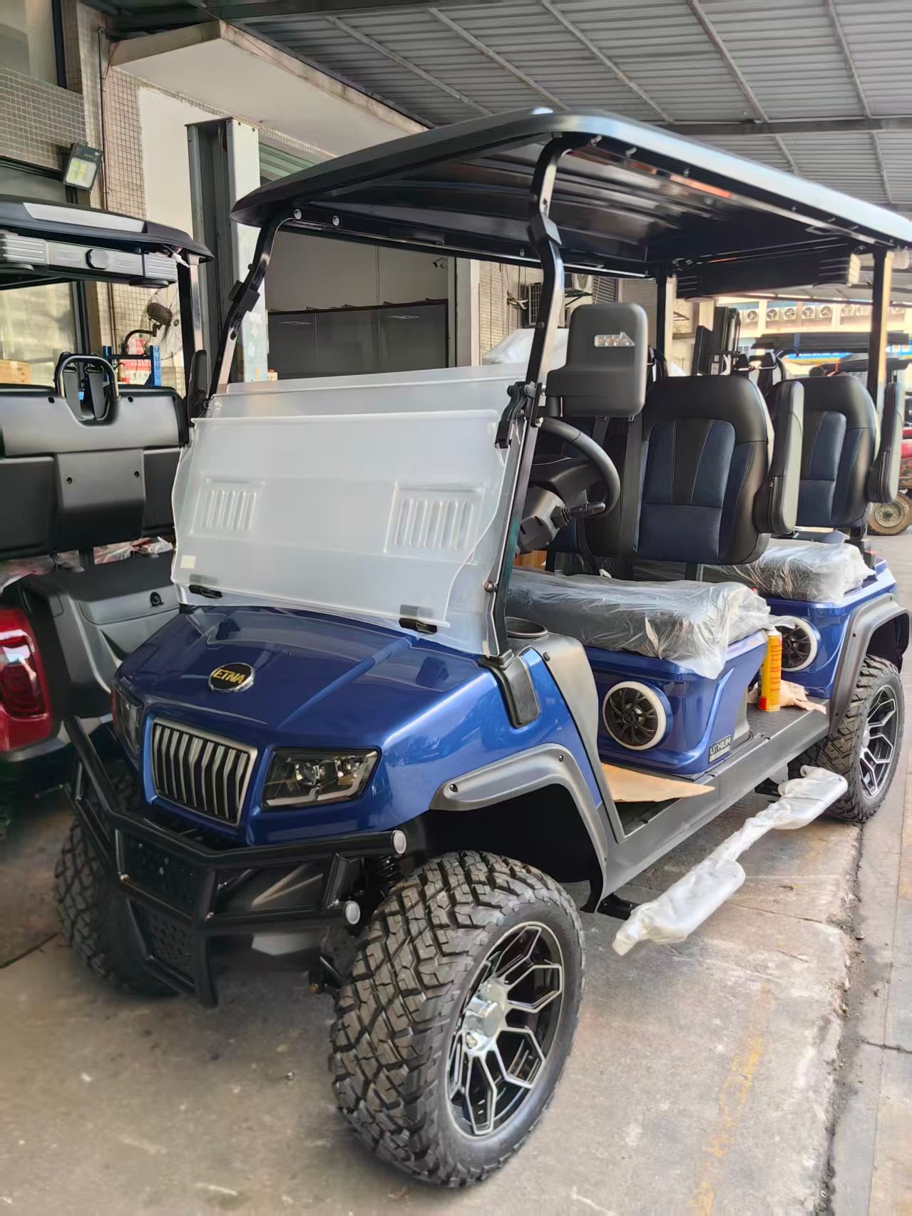 Blue Etha golf cart with black bumper, off-road tires, and silver grill.
