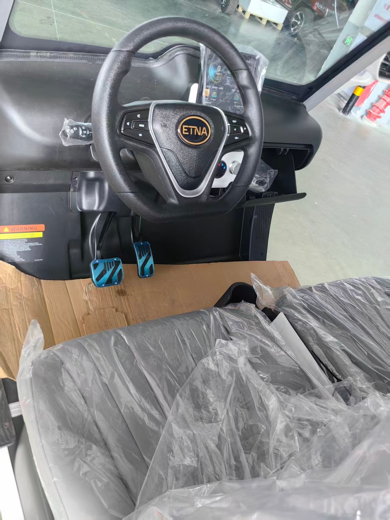 White golf cart with black wheels, parked indoors.