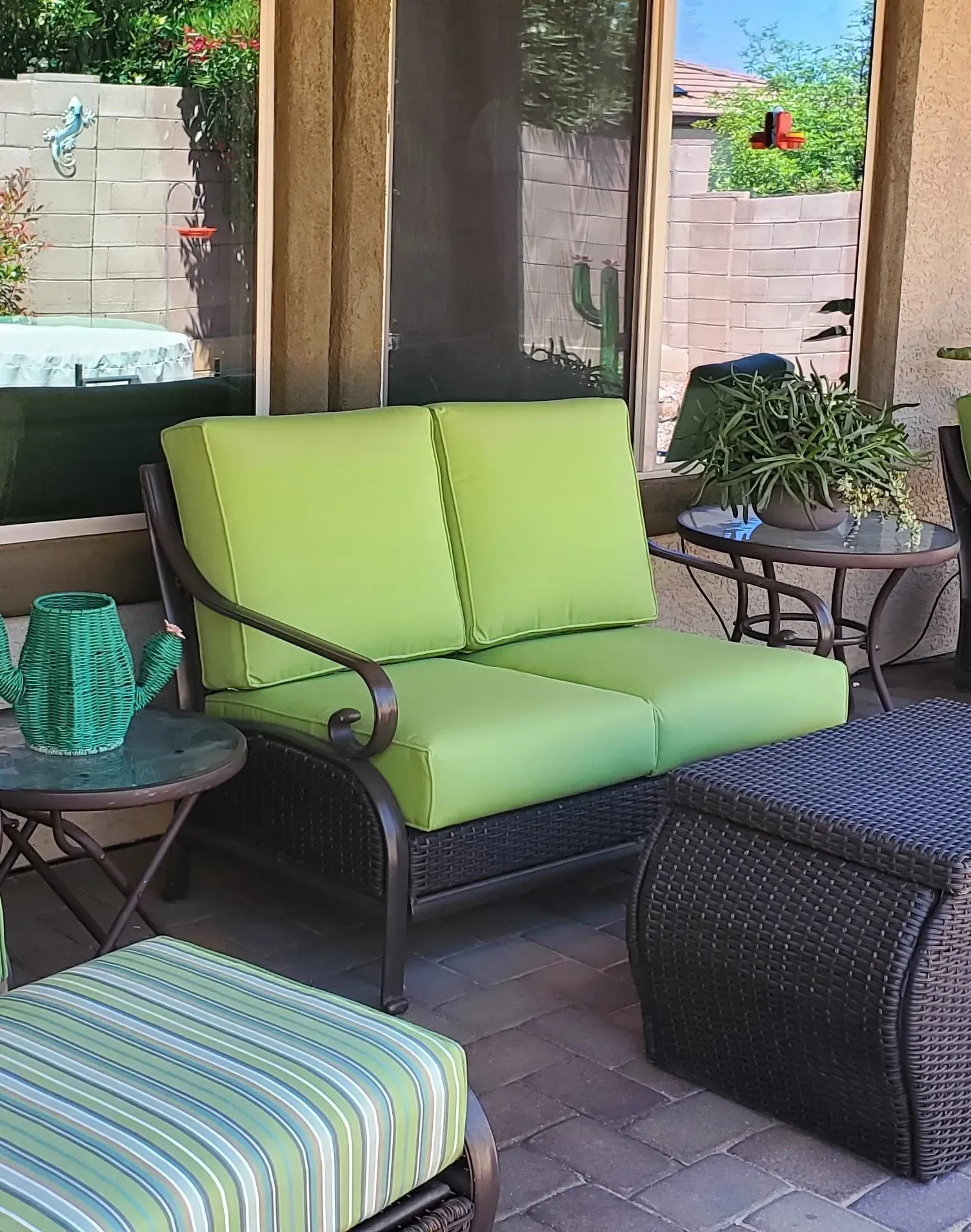 A patio with a couch and ottoman with green cushions