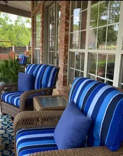 A porch with blue and white striped chairs and a table.