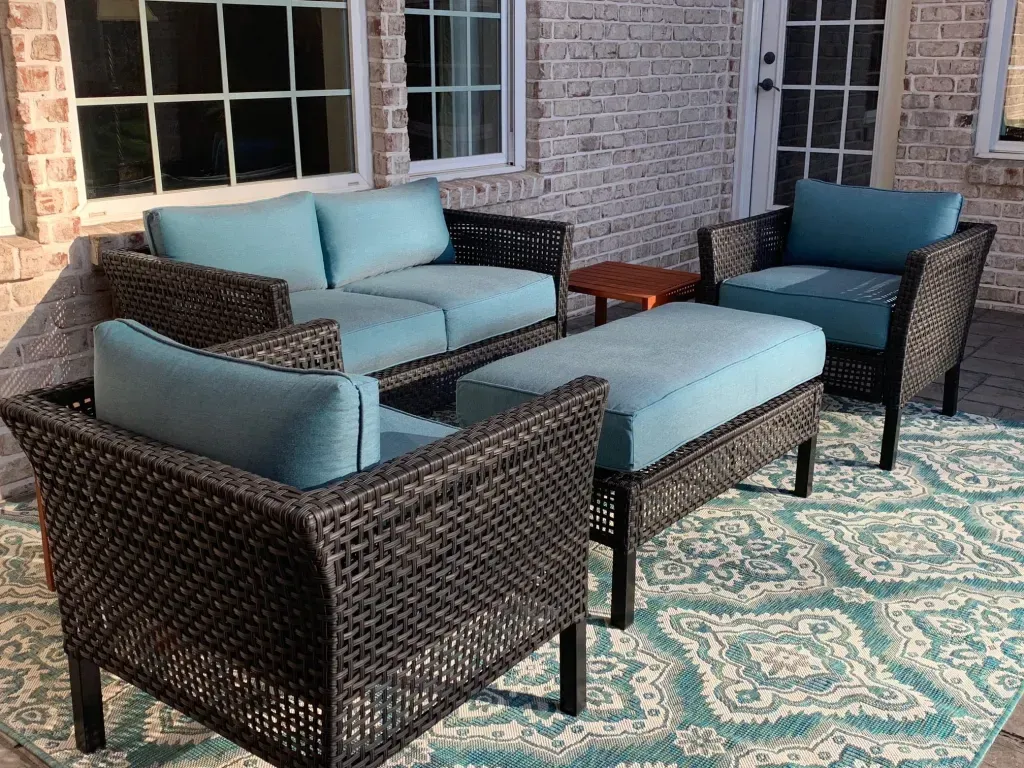 A patio with wicker furniture and a blue rug