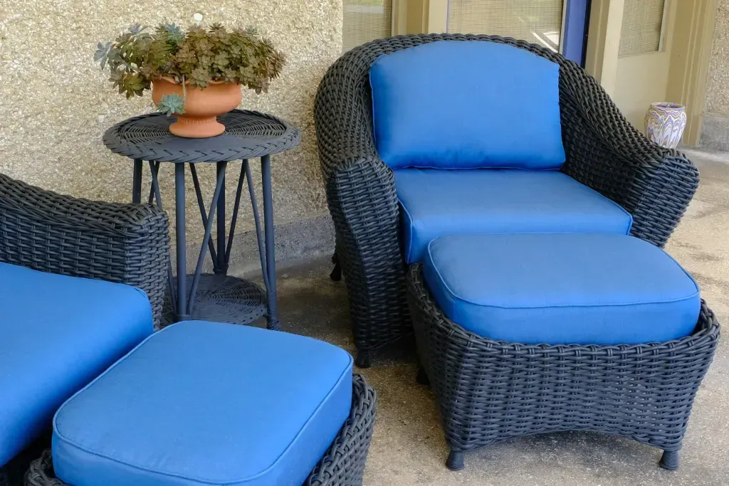 A wicker chair and ottoman with blue cushions