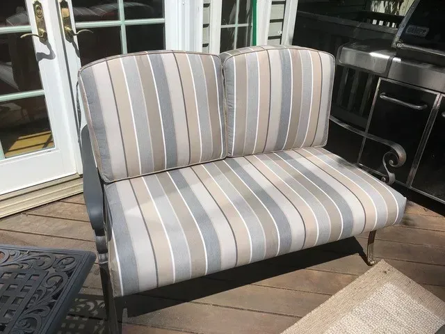 A striped couch is sitting on a wooden deck.