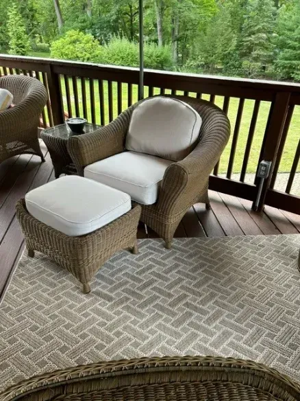 A wicker chair and ottoman are on a deck.