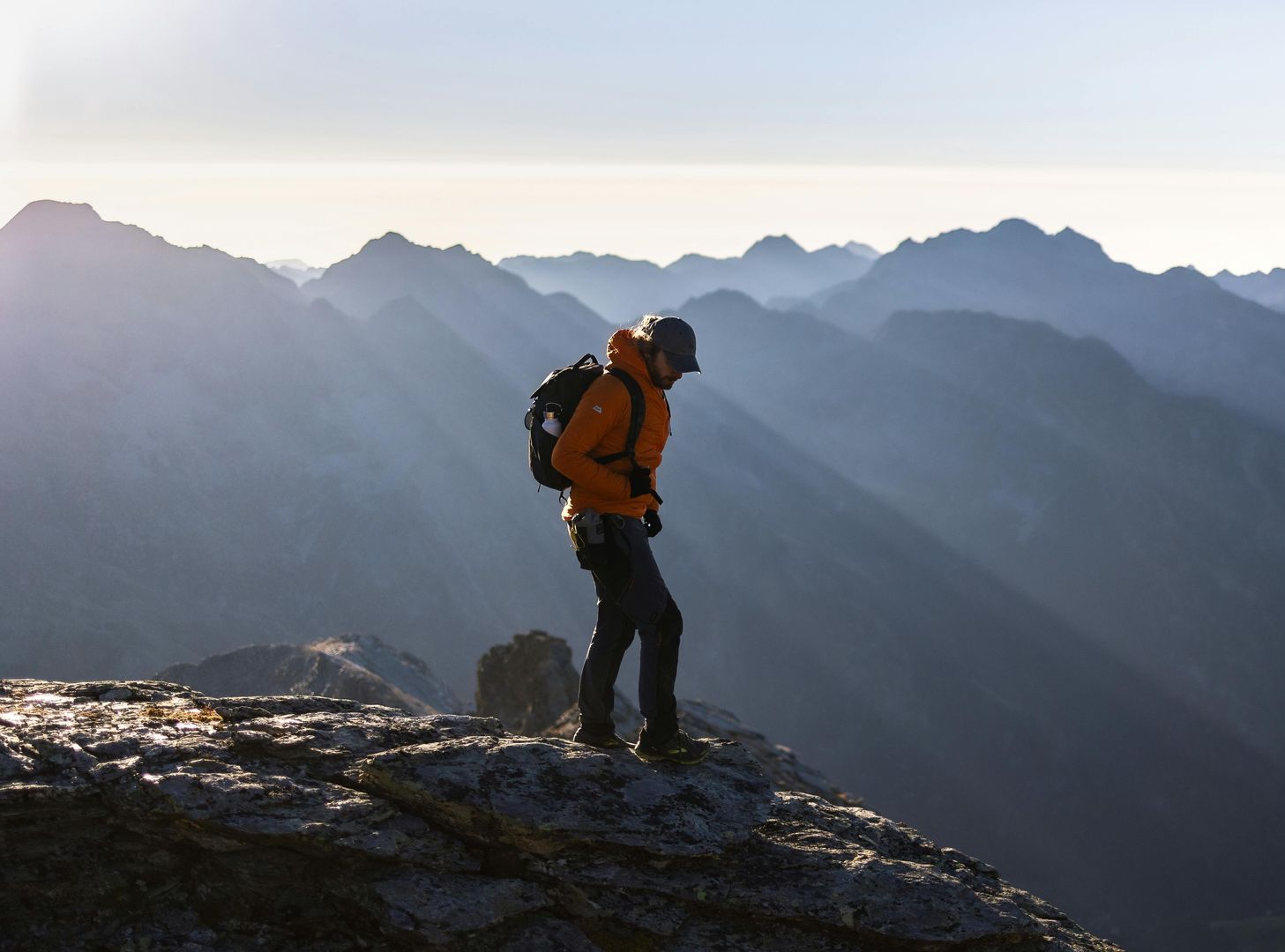 A man with a backpack is standing on top of a mountain
