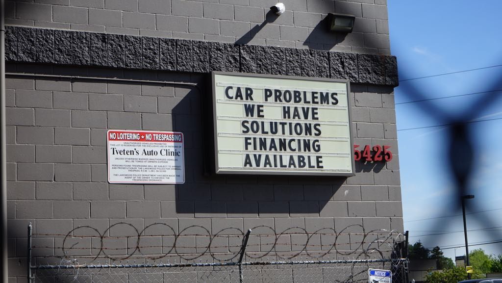A sign on the side of a building says car problems we have solutions financing available