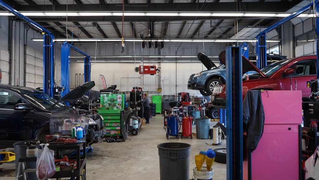 A garage filled with lots of cars on lifts and tools.