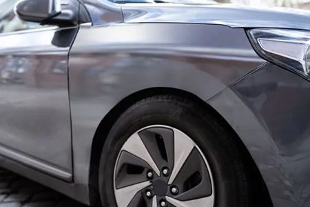 Gray car's front quarter, showing tire and wheel; a dark gray body and silver rims.