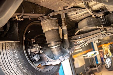 Undercarriage of a vehicle with a black air suspension strut and wheel visible.