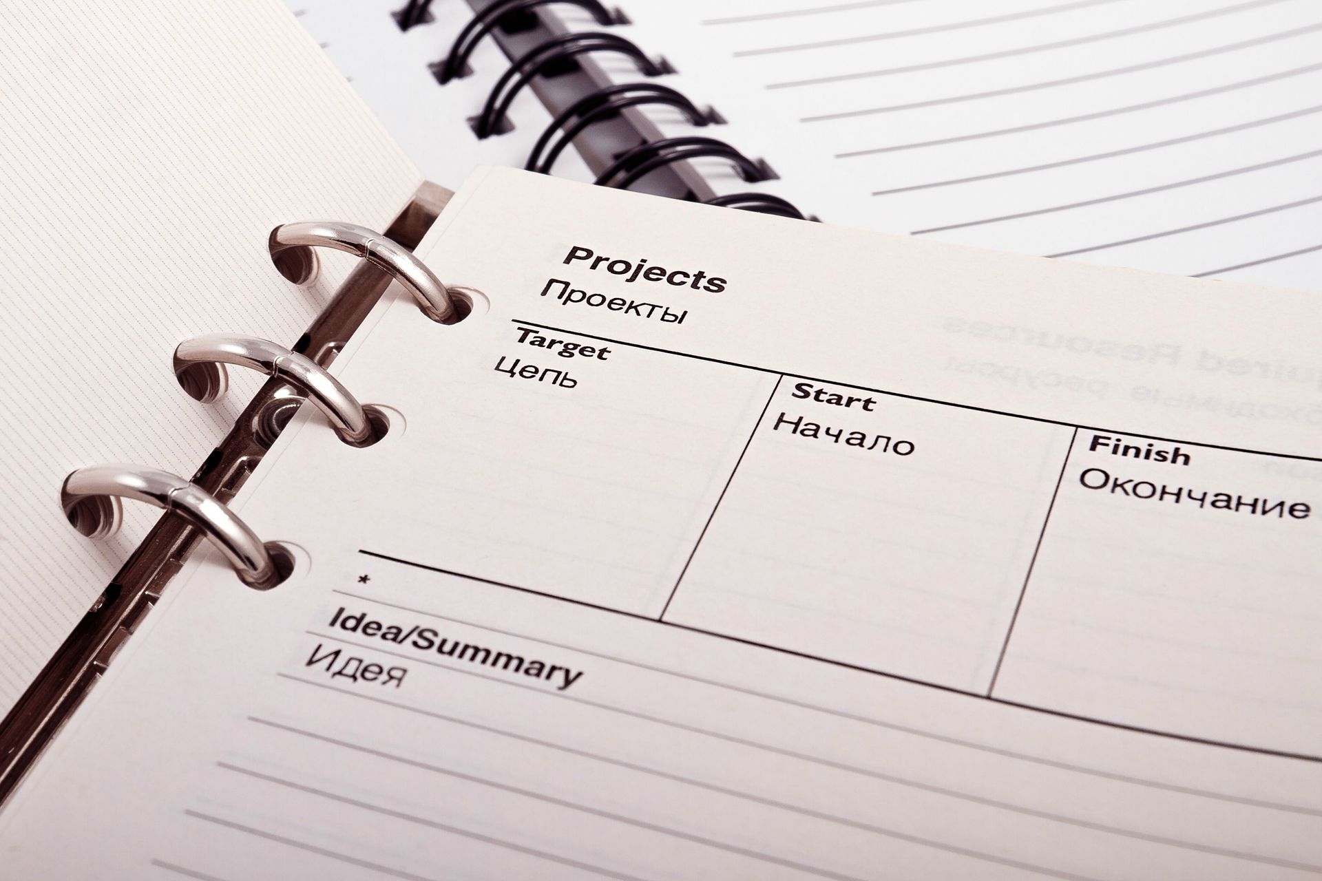 Close-up of an open spiral notebook with a monthly planner layout and handwritten notes on lined paper