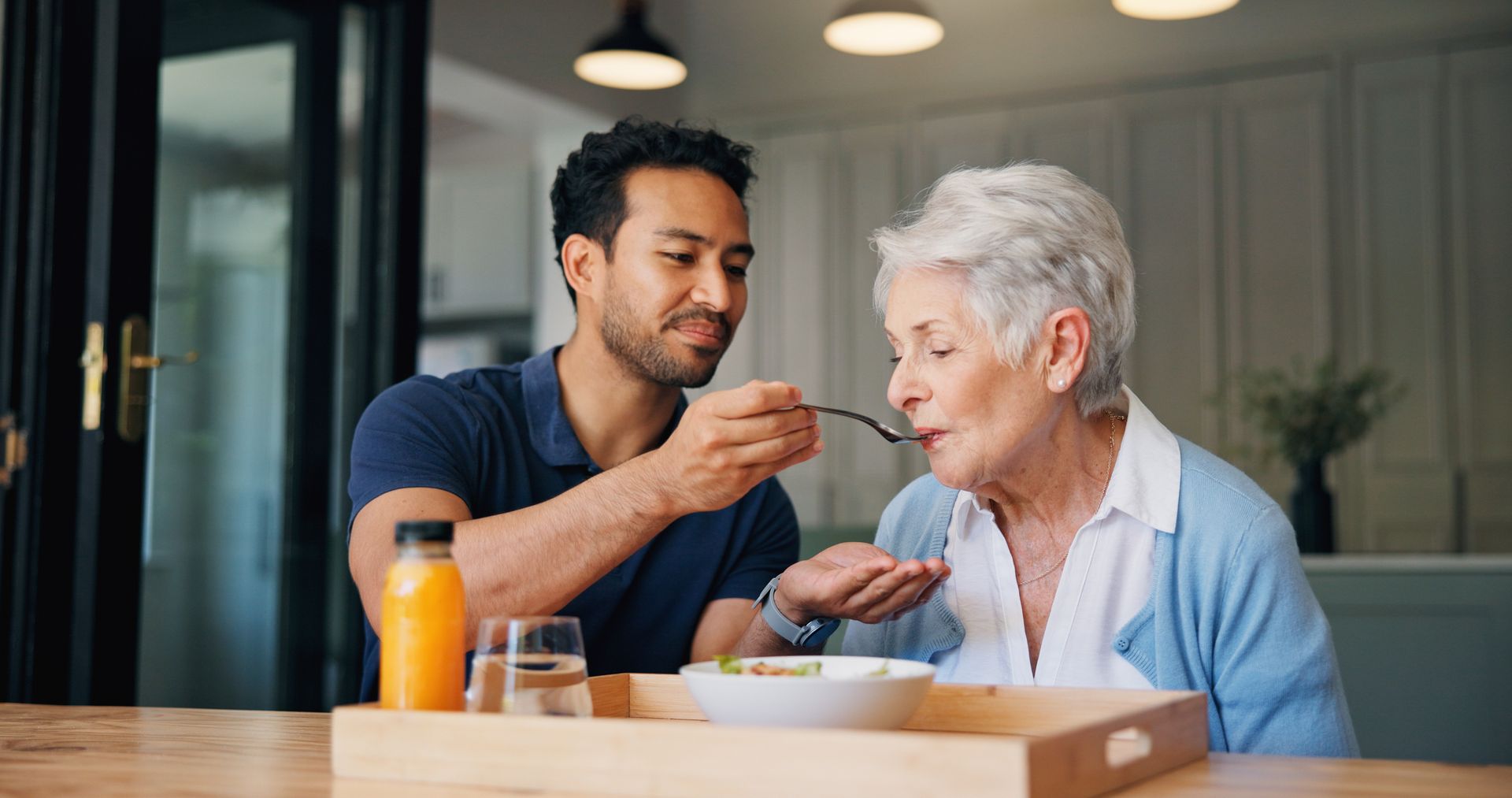 A caregiver is feeding an elderly woman.