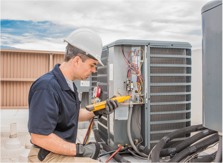 A man wearing a hard hat is working on an air conditioner.