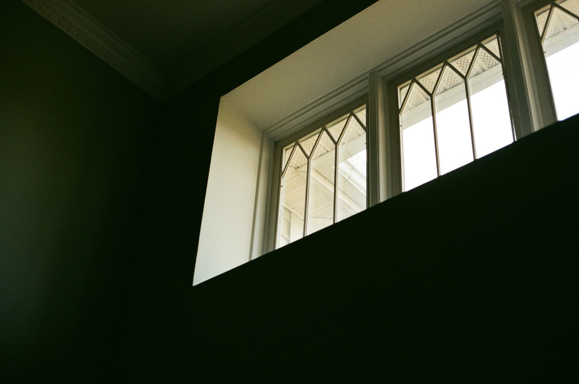 Wooden church pews in a dimly lit room, with a beam of light shining across them.