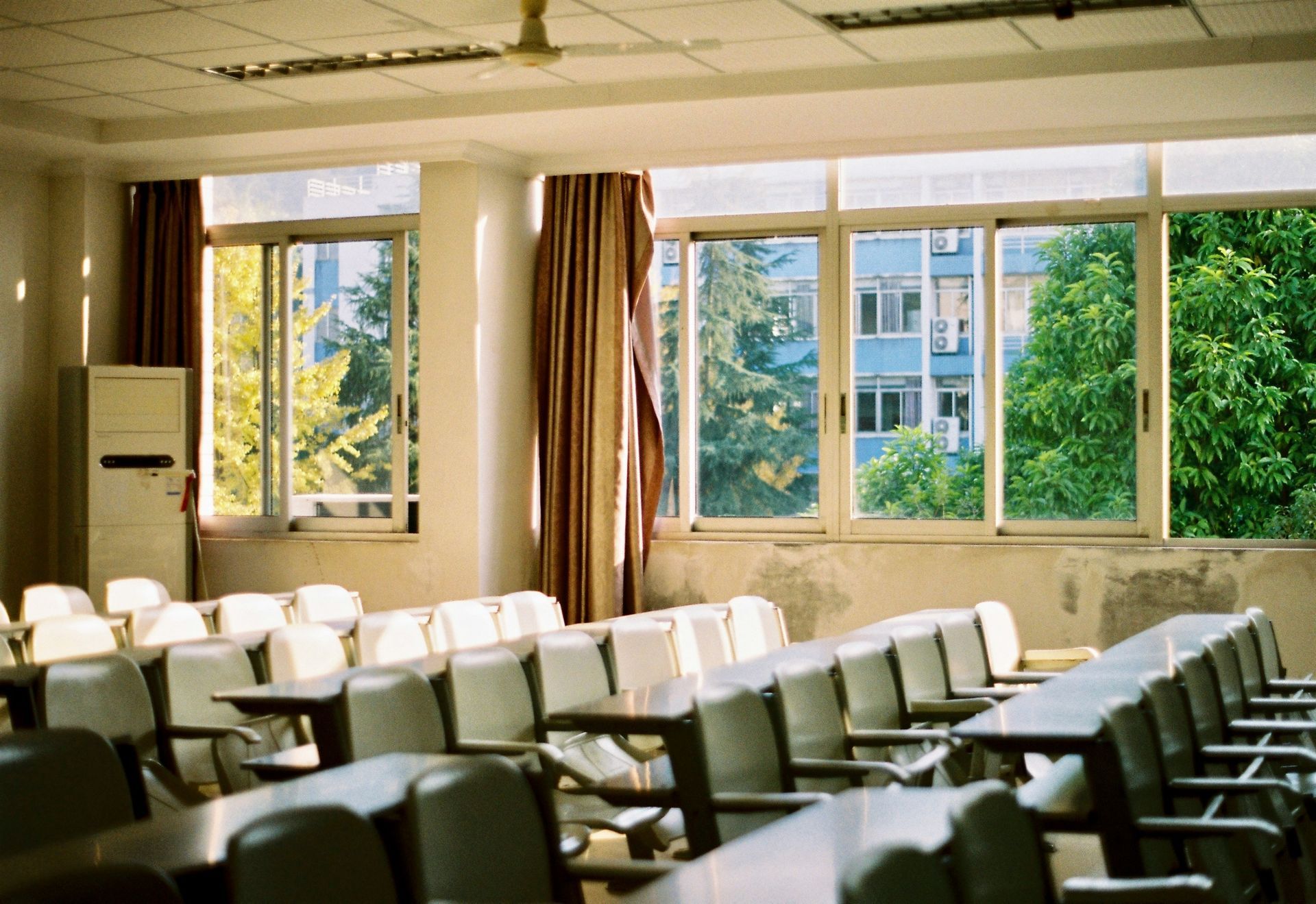 Empty classroom with rows of desks, windows, and natural light streaming in.