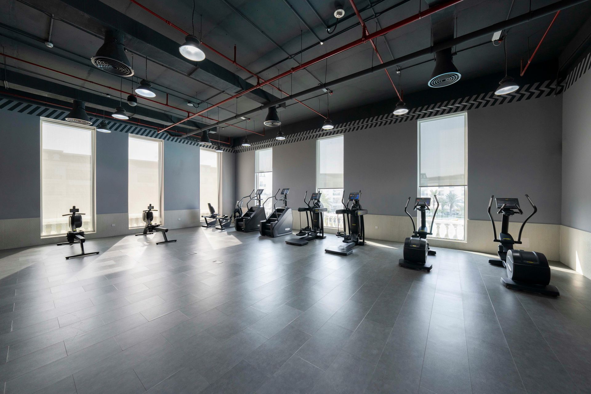 Gym with exercise equipment, gray walls, and windows.