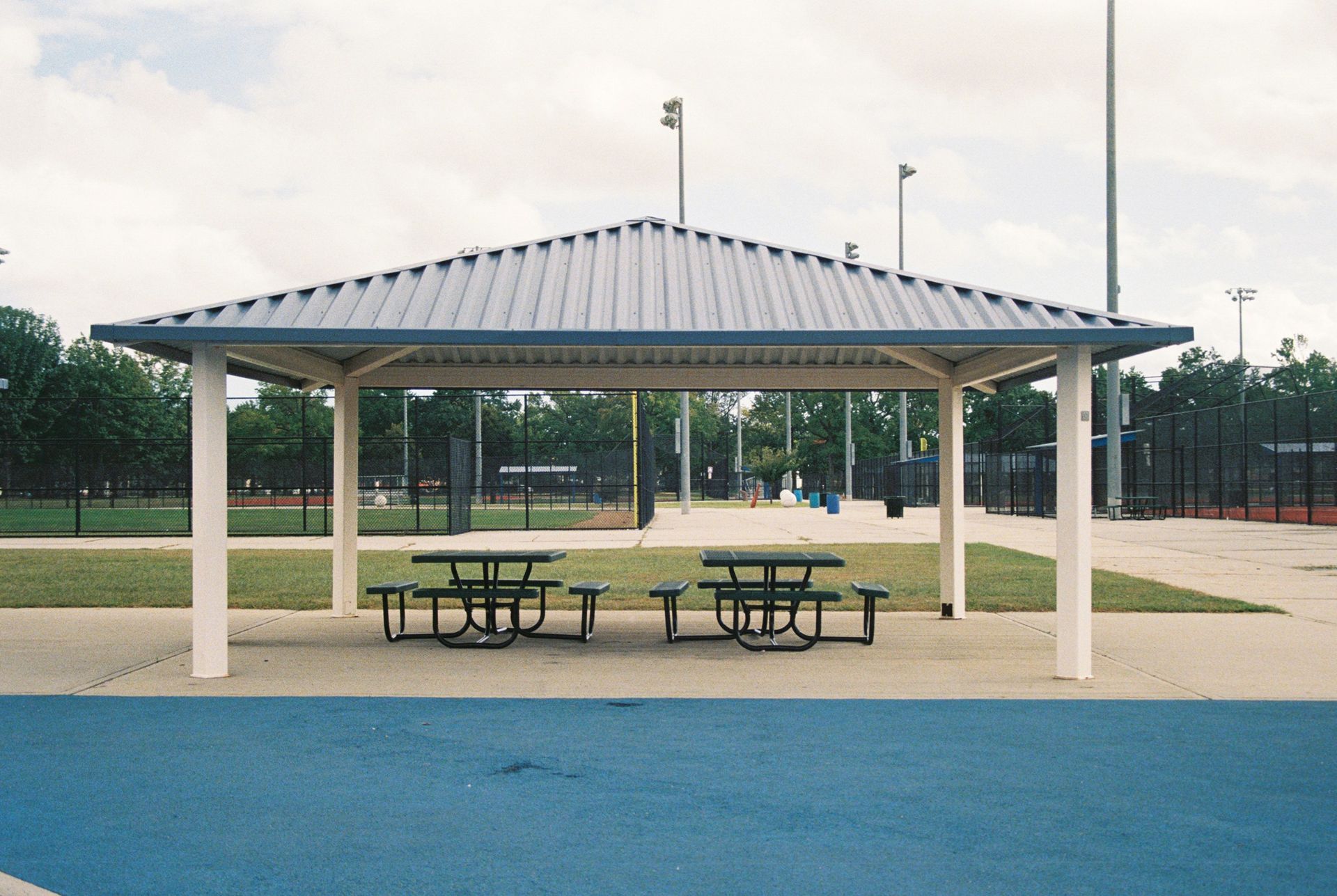 Interior of a library with tables, chairs, computers, and bookshelves. Sunlight streams through windows.