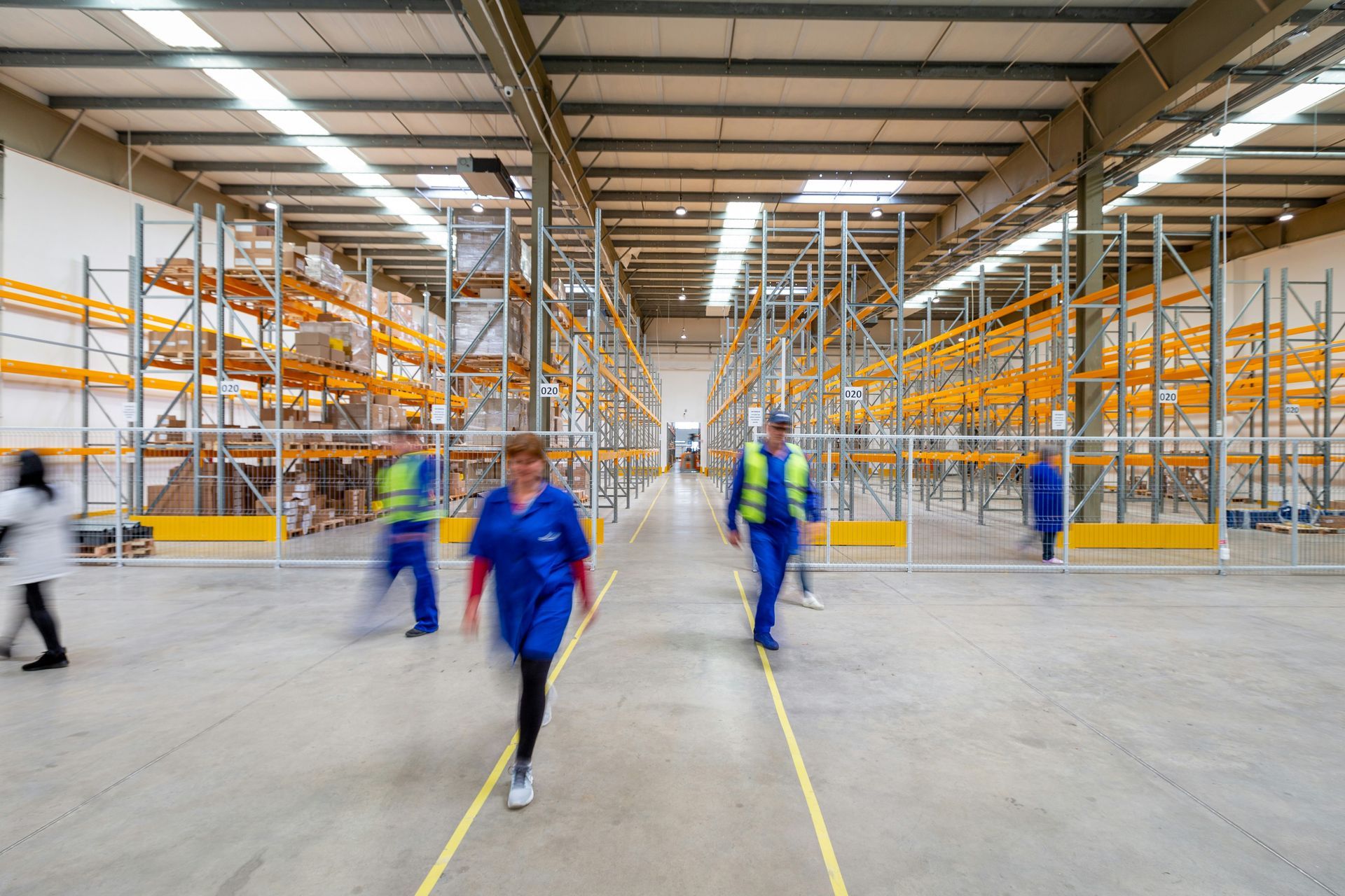 Warehouse interior with boxes and pallets wrapped in plastic. Hand truck on the left.