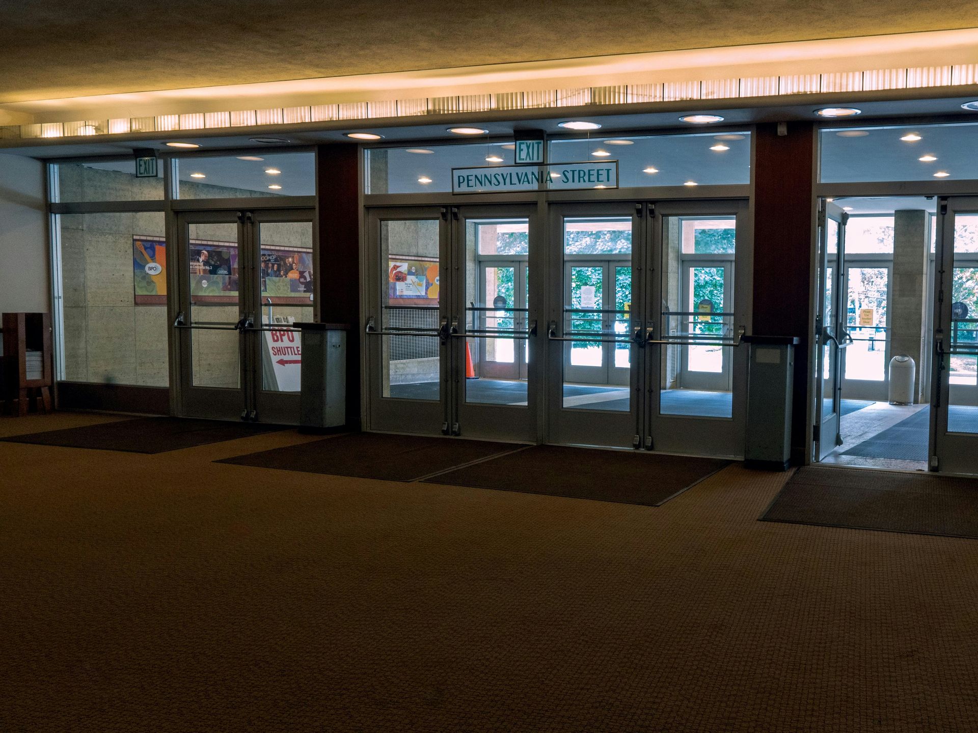 Rows of empty chairs face a stage in a large, empty conference room.