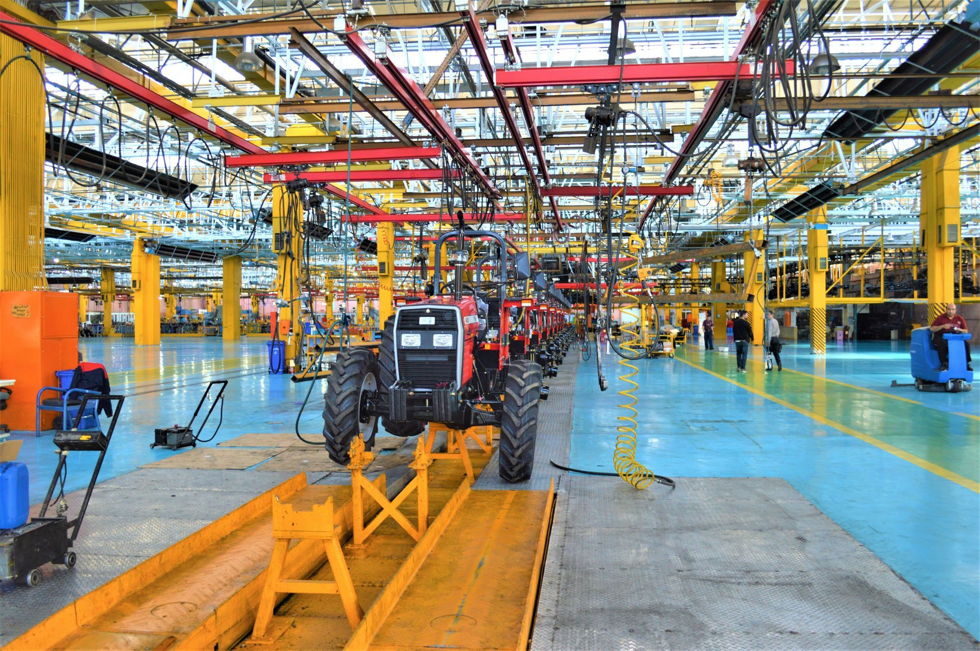 Tractors on an assembly line inside a brightly lit factory.