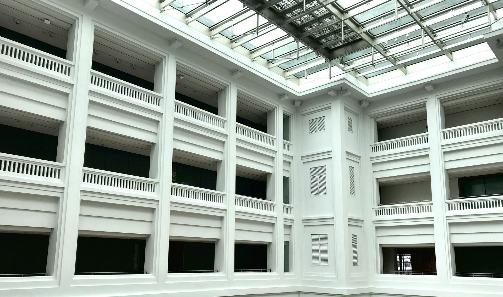 Empty ballroom with large windows, dark carpet, and hanging chandelier.