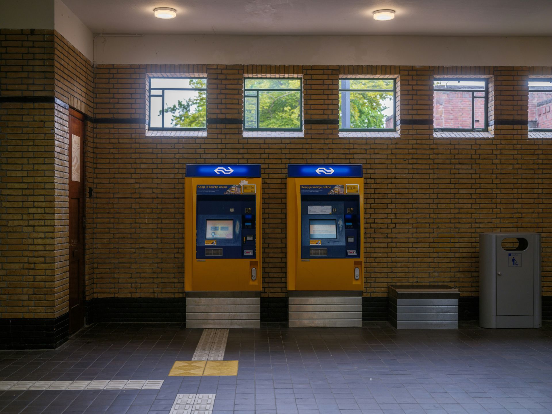 Bank teller booths with brass rails and globe lamps, interior shot.