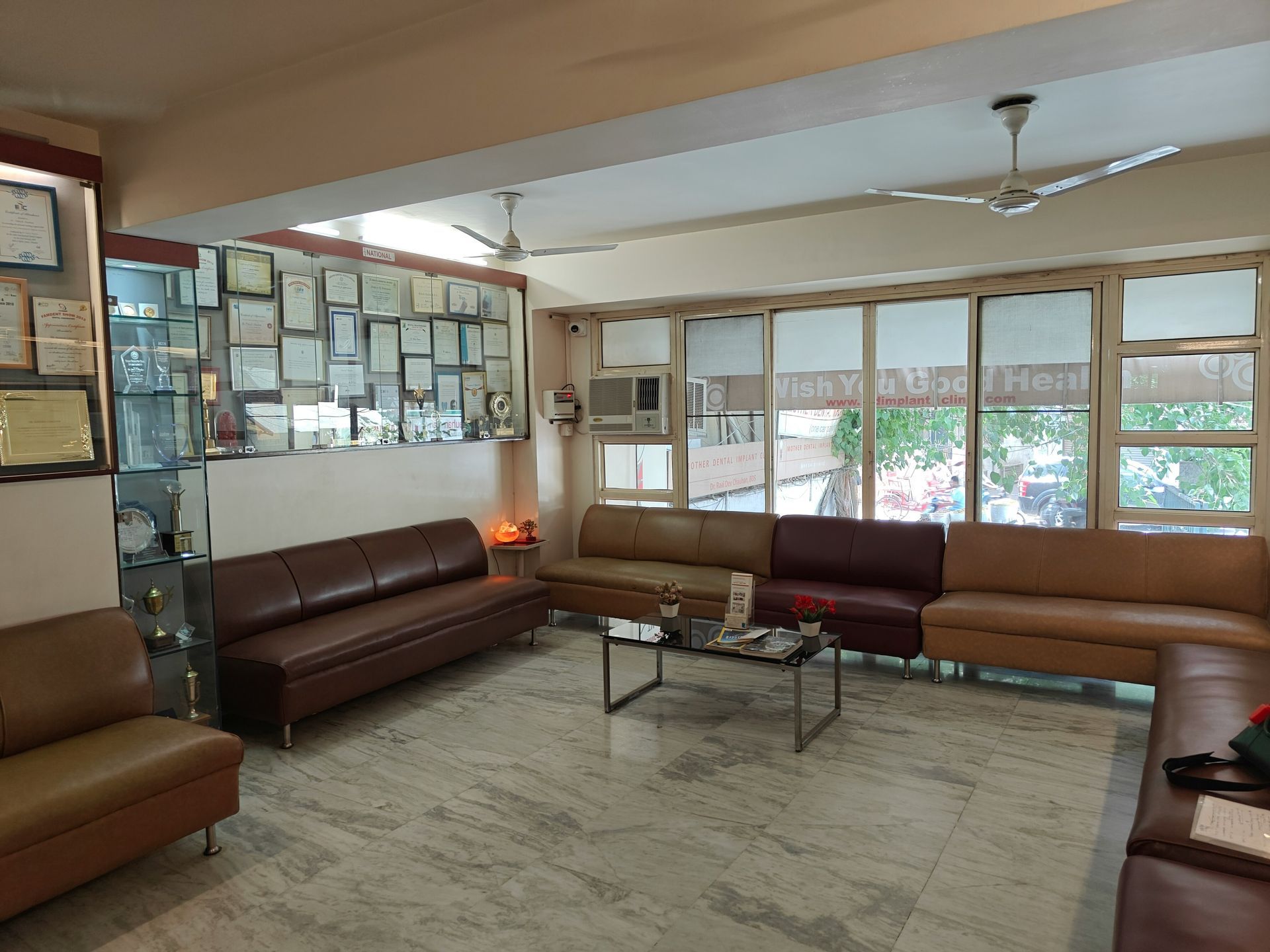Interior of a church with rows of wooden pews facing an open doorway to a grassy area. Bright natural light.