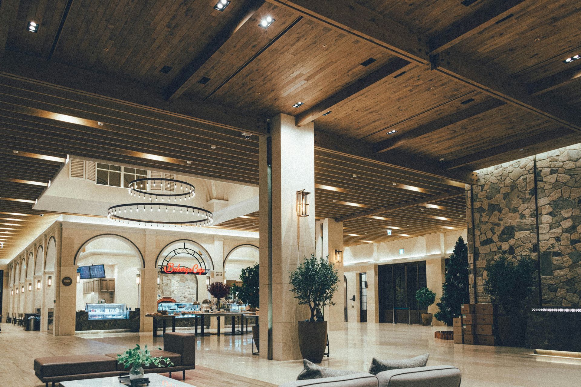 Spacious hotel lobby with wood ceiling, stone accent wall, seating, and reception area.