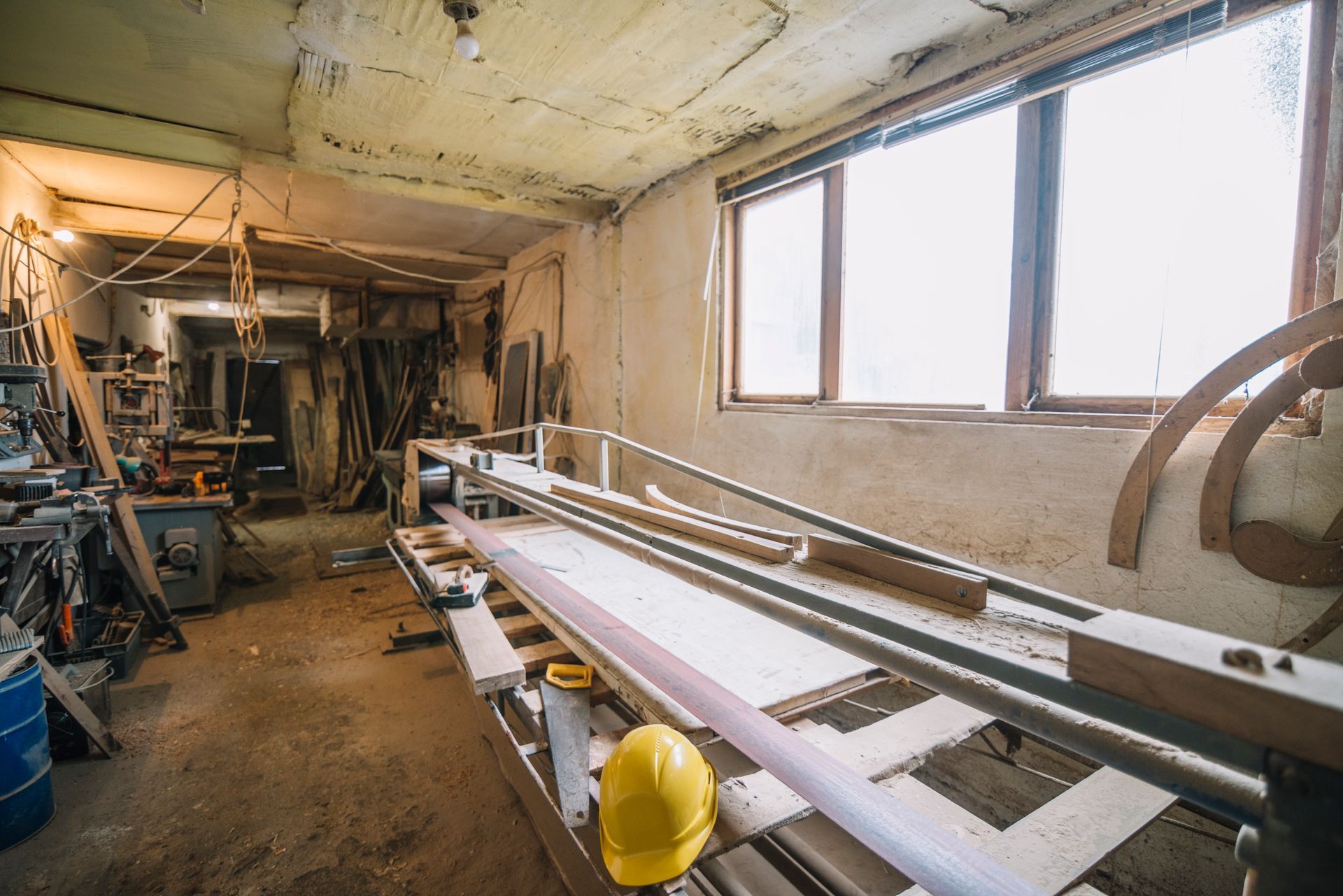 A large industrial sewing workshop with numerous tables, fabric, and spools of thread; neutral tones and fluorescent lights.