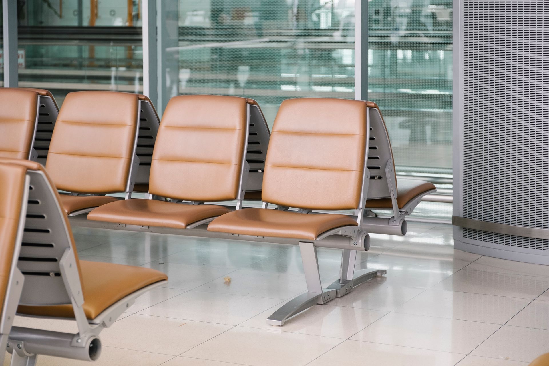 Brown seats in an hospital waiting area, with a window behind them.
