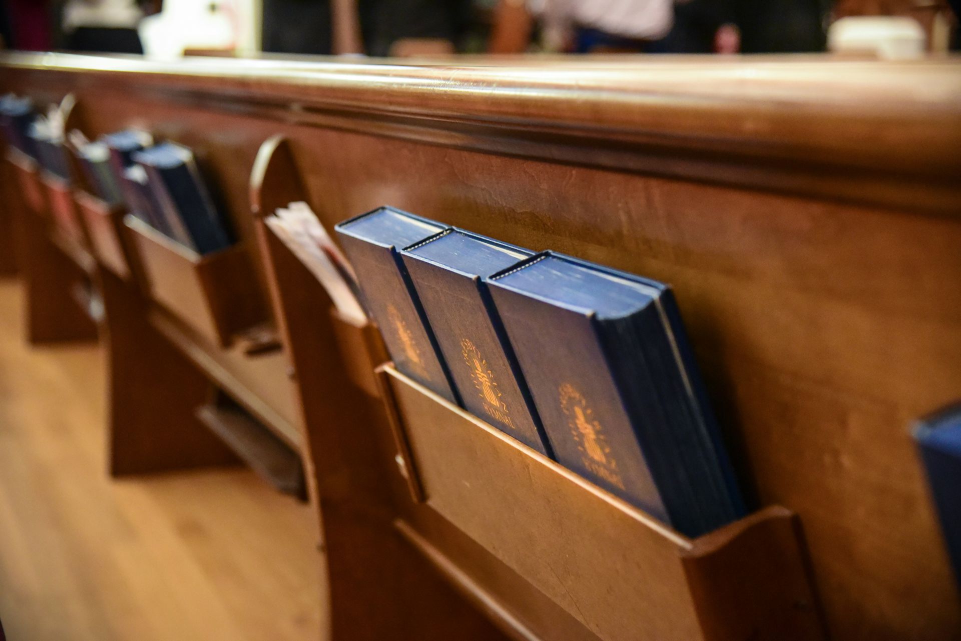 Interior of a church with a wooden ceiling, altar, and pews. A cross hangs above the altar.