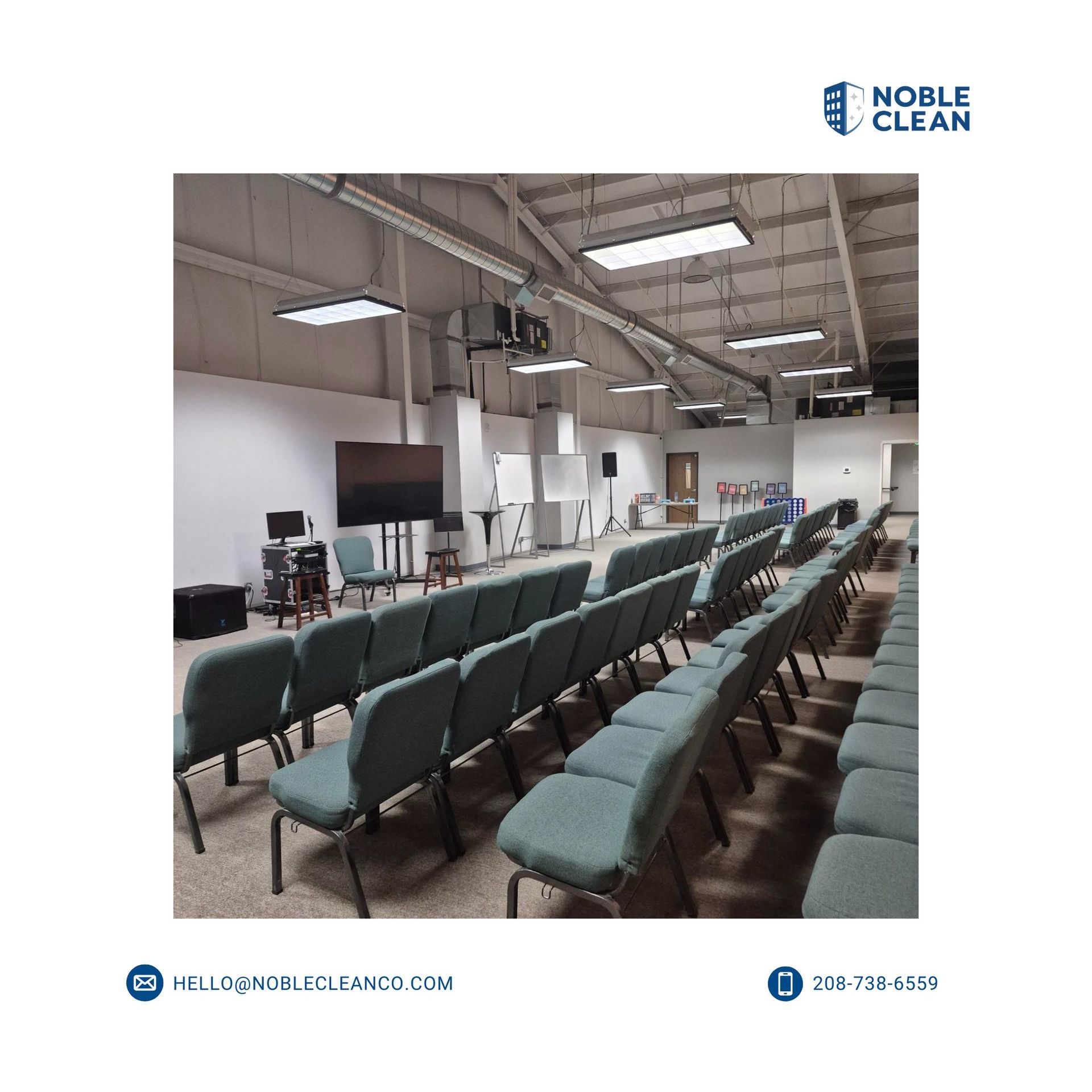 Empty rows of green fabric chairs in a brightly lit, industrial-style conference or meeting hall.