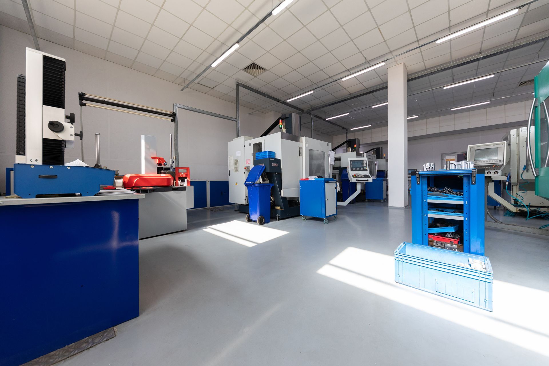 Machine shop interior with white machines, blue cabinets, and a measurement device.